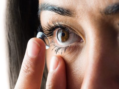 Woman about to insert her contact lens against a white background